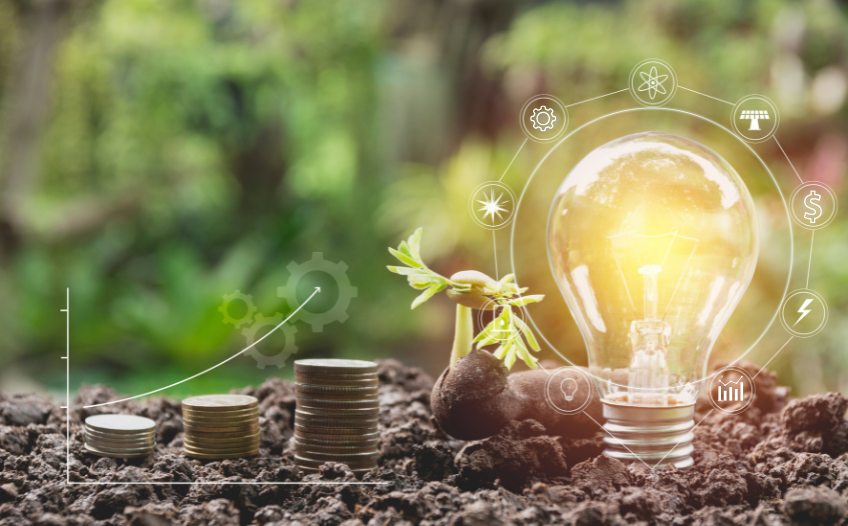 Image with lightbulb and stacked coins on soil. Nature background.