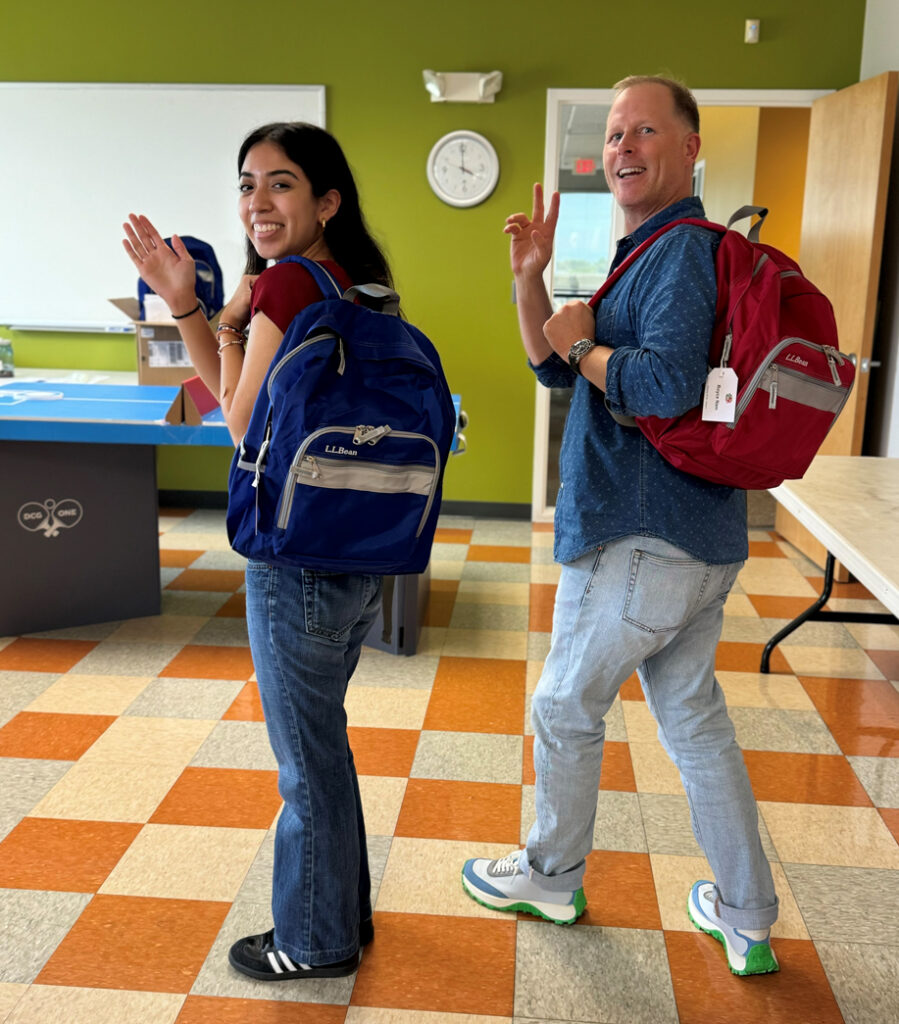 Intern Andrea Flores (from Montgomery College) stuffing backpacks (L) for back to school kids with supervisor Jaime Grams (R).